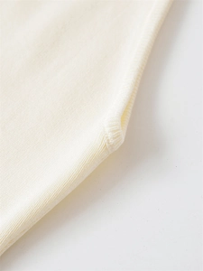 Macro shot of cream knit sweater fabric showing detailed soft texture and seaming