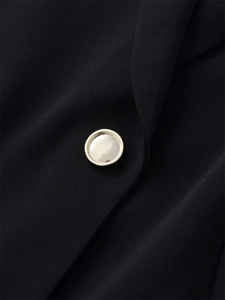 Detailaufnahme eines silbernen Knopfes an einem schwarzen Blazer mit edler Stofftextur
