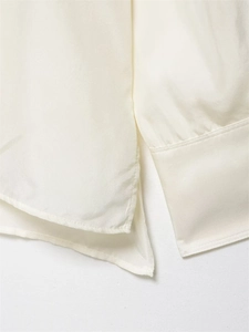 Detail of silk shirt showing cream fabric texture, side slit and refined stitching