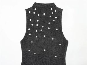 Gros plan du haut en tricot sans manches gris foncé avec boutons perlés et col montant