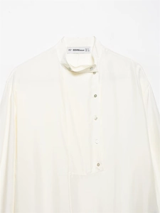 Detailed view of the brand label on a premium cream silk shirt with elegant satin texture