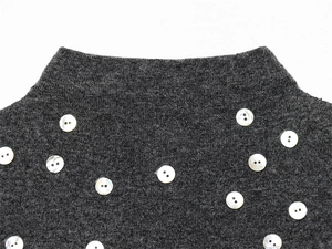 Gros plan d'un haut en maille gris foncé avec détails de boutons en perles blanches