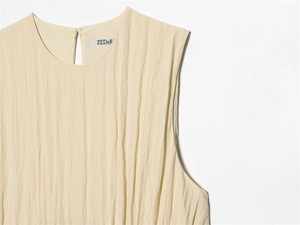 Gros plan détaillé de la robe beige sans manches montrant la texture plissée du tissu
