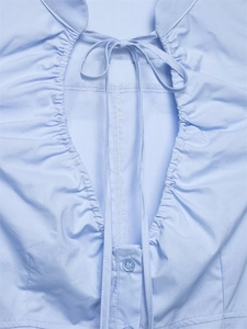 Dettaglio camicia in popeline azzurro con scollo a pieghe e fiocco decorativo sottile