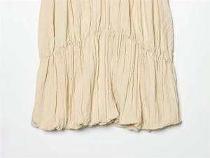 Vue détaillée du tissu plissé beige clair avec coutures froncées et texture fine