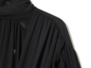 Detailed macro shot of black pleated chiffon fabric with fine neck and shoulder stitching
