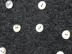 Vue détaillée de la texture laine grise et des boutons en nacre sur la robe