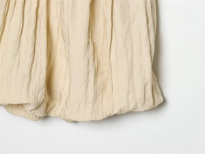 Macro du bas de robe beige montrant la coupe bouffante et la texture du tissu