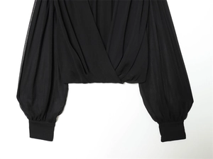 Detail of elegant black wrap blouse with deep V-neckline and puffy lantern sleeves