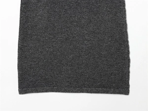 Détail de l'ourlet en maille gris foncé et des coutures précises d'une robe courte