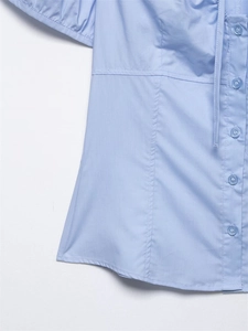 Dettaglio della camicia in popeline azzurro con bottoni tondi e cuciture verticali sciancrate