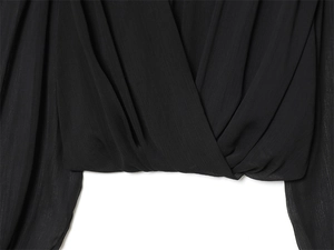 Detail of black wrap-style top showing fine vertical texture and overlapping design