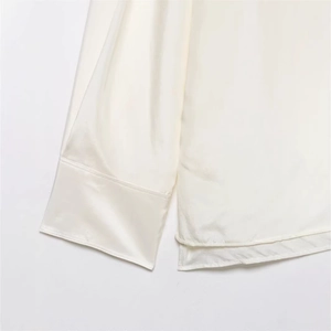 Detailed view of cream silk satin blouse featuring wide cuffs and side split hem