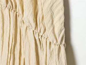 Gros plan sur tissu crémeux plissé seersucker montrant les détails de texture smockée