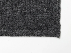 Gros plan sur la texture du tricot gris foncé avec détails de couture sur le bord