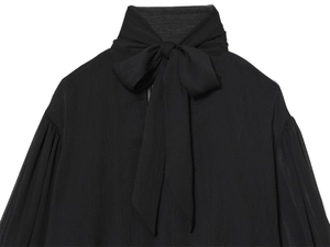 Detailed close-up of textured black blouse featuring high neck bow and lantern sleeves