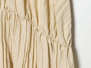 Détail macro des plis verticaux et du tissu texturé sur cette robe ballon crème