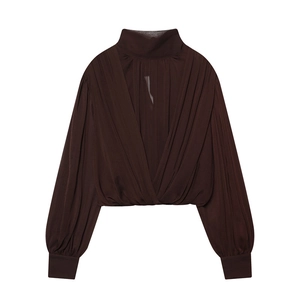 Detail of V-shaped draped pleats on a brown long-sleeved blouse with lantern sleeves