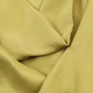 Détail du tissu satiné vert olive avec texture lisse et plis drapés élégants