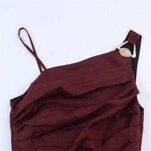 Gros plan d'une robe asymétrique bordeaux avec anneau en métal doré et détail en marbre