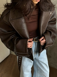 Detail of a brown oversized faux leather jacket featuring a lapel collar and rich texture