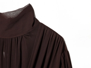 Detail view of high-neck pleated chiffon top in dark brown with elegant texture