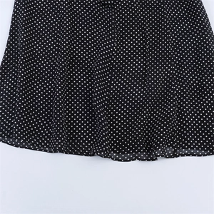 Detailed macro view of black midi dress fabric with white polka dot pattern print