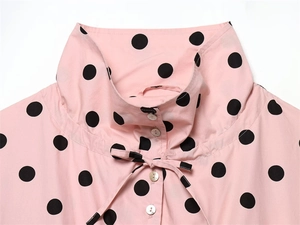 Detail of pink polka dot jacket showing high collar bow tie and pearl finish buttons
