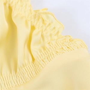 Abito in raso giallo chiaro con delicati volant e texture elastica a nido d'ape