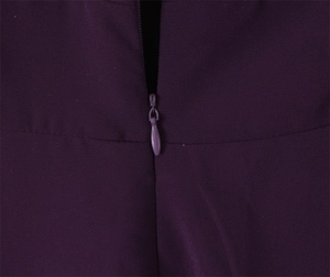 Close-up of deep purple slim-fit dress showing invisible back zipper and matte fabric texture
