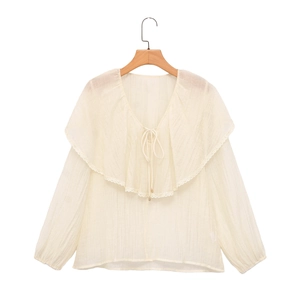 Dettaglio camicia in chiffon color crema con ampio colletto a volant e lacci al collo