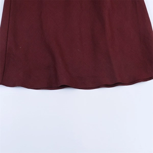 Détail macro de la texture du lin bordeaux et de la couture de l'ourlet de la robe