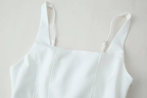 Detailed close-up of white mini dress featuring square neckline and adjustable straps