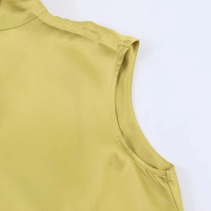 Détail d'une chemise en satin jaune moutarde avec col montant et coutures de précision
