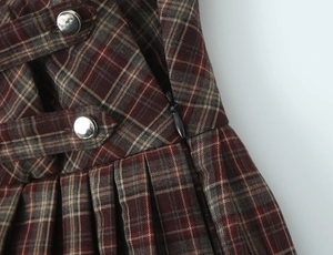 Détail de la taille de jupe plissée à carreaux avec boutons décoratifs et zip invisible