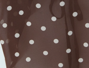 Vue détaillée du tissu en mousseline marron léger avec d'élégants pois blancs