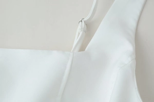 Close-up of adjustable spaghetti straps and metal rings on a white summer mini dress