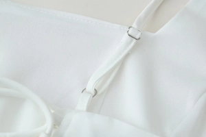 Detail view of white dress with adjustable silver metal buckles and thin spaghetti straps