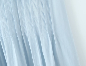 Detailed close-up of vertical pleats and fine stitching on a light blue summer dress