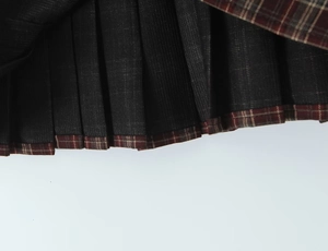 Détail de la jupe plissée à carreaux gris foncé avec ourlet bicolore cousu