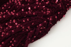 Detailopname van luxe bordeauxrode fluwelen stof met glinsterende lovertjes