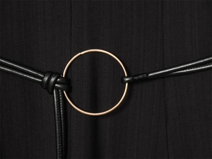 Détail d'une fine ceinture en cuir noir avec une grande boucle ronde en métal doré