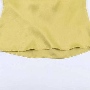 Détail de la blouse en satin jaune olive montrant l'ourlet arrondi et la texture