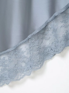 Detailed close-up of light blue silk-textured satin fabric with delicate floral lace trim