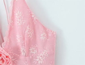 Dettaglio di abito in pizzo rosa con ricami floreali e fiori decorativi in pizzo 3D