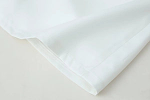 Detailed macro view of white dress fabric showing high-quality double stitching and texture