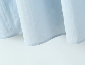 Detail view of high-quality stitching and light blue cotton fabric on dress hem