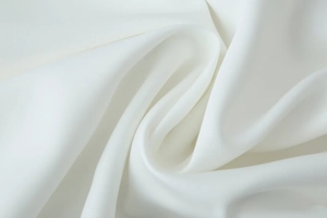 Macro shot of white silk-textured fabric showing smooth drape and elegant pleated details