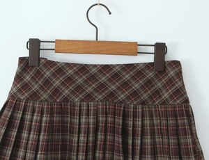 Détail de la jupe plissée à carreaux rouge et marron montrant la texture du tissu