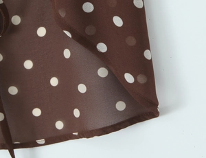 Gros plan sur un tissu en mousseline marron à pois blancs avec ourlet délicat
